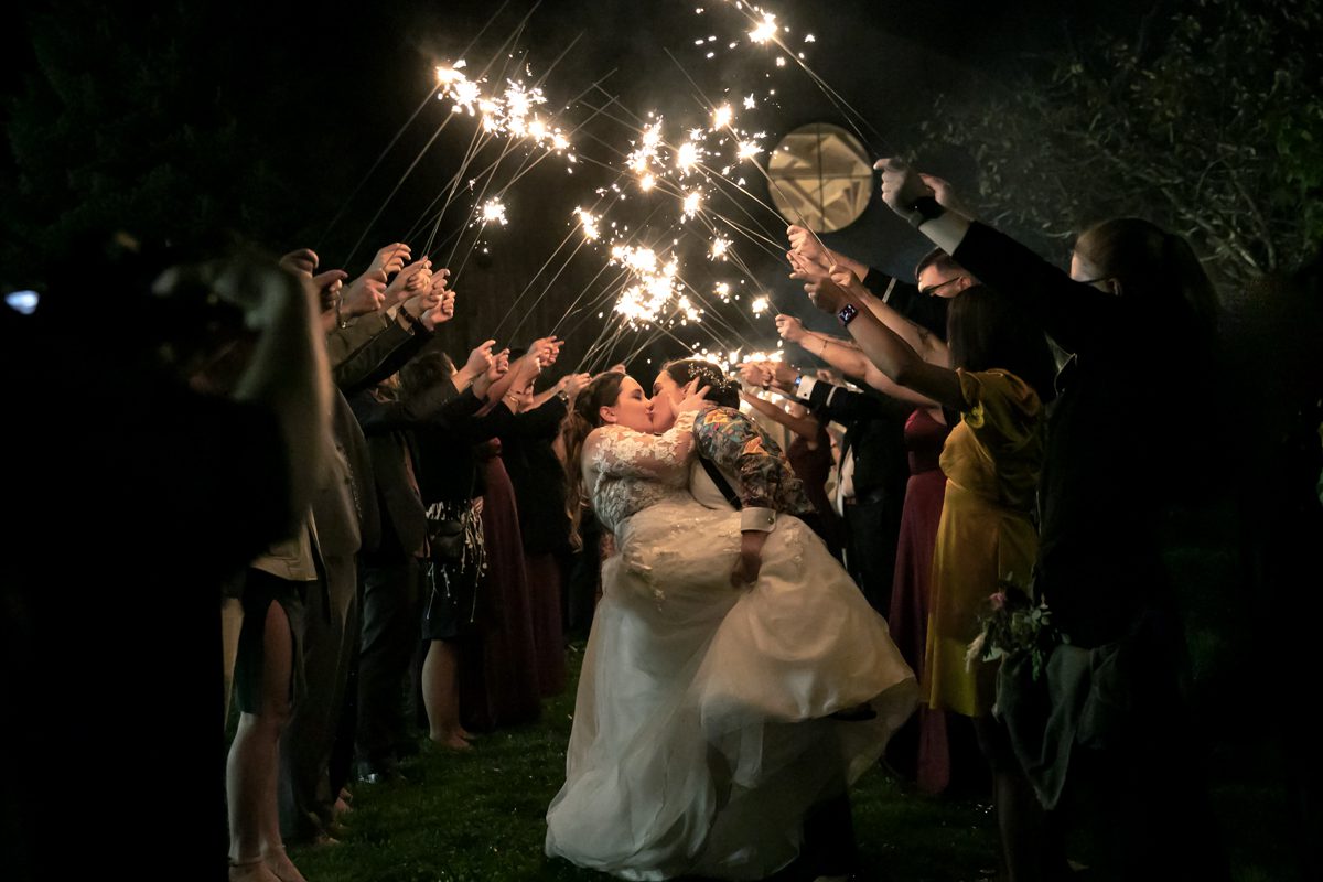 A bride and groom kissing in front of a crowd.