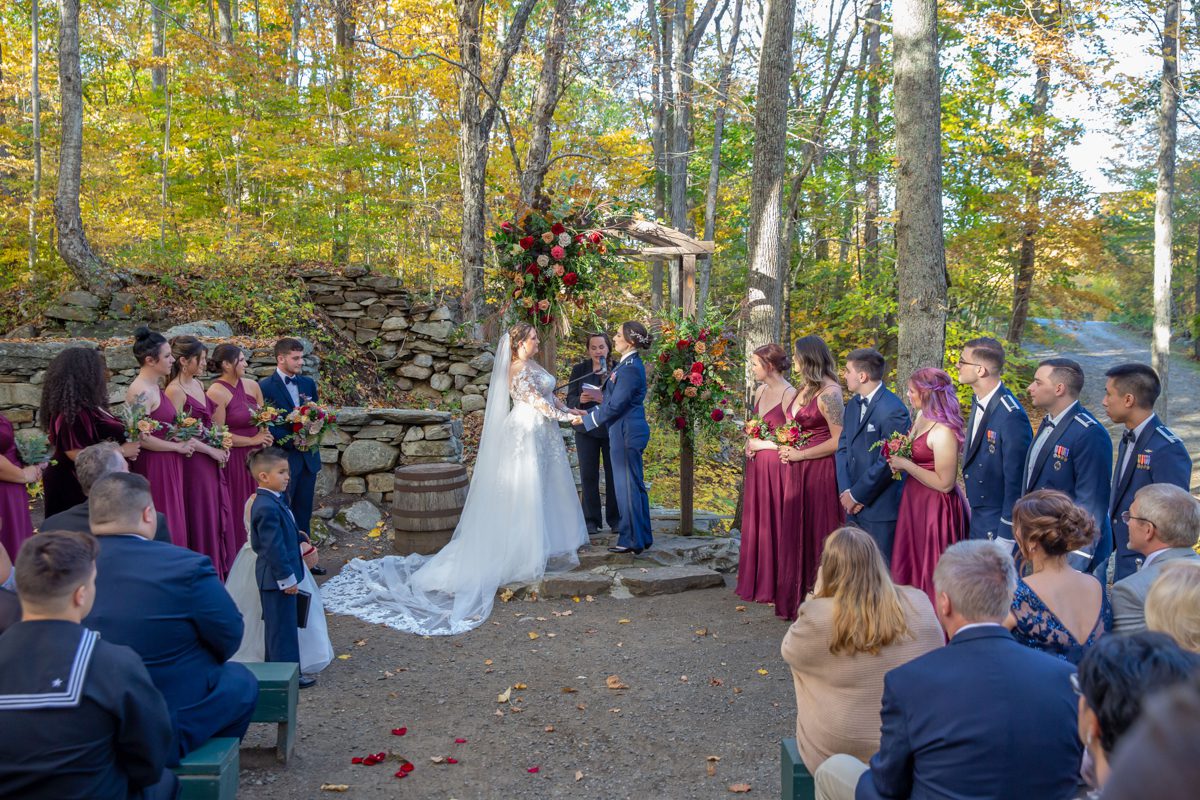 A bride and groom are holding hands as they stand in front of their wedding party.