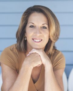 Smiling woman with hands clasped.